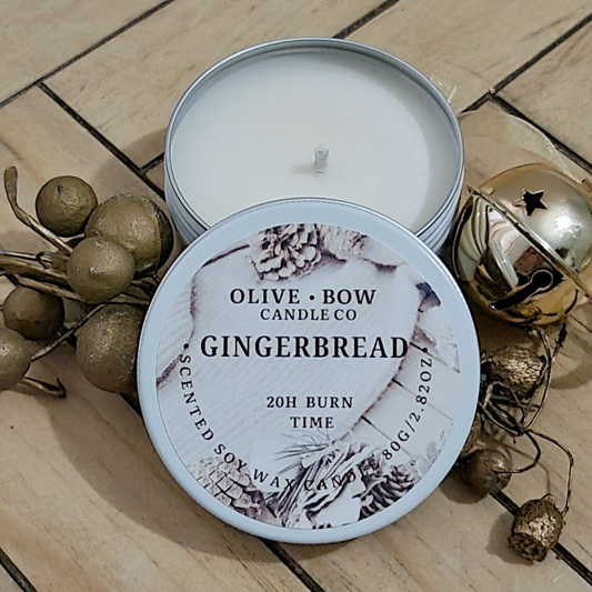 Gingerbread scented Soy candle in a tin with decorative elements on a wooden surface. Made by Olive Bow Candle Co