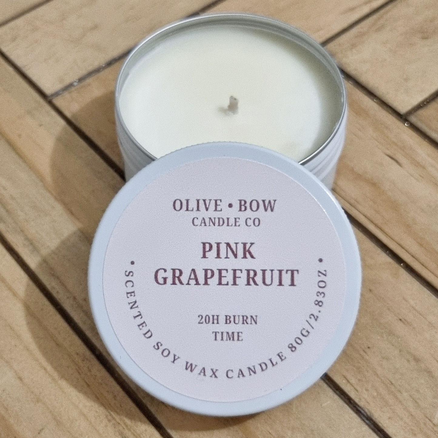 Soy candle in a white tin, in the scent Pink Grapefruit. Made by Olive Bow Candle Co